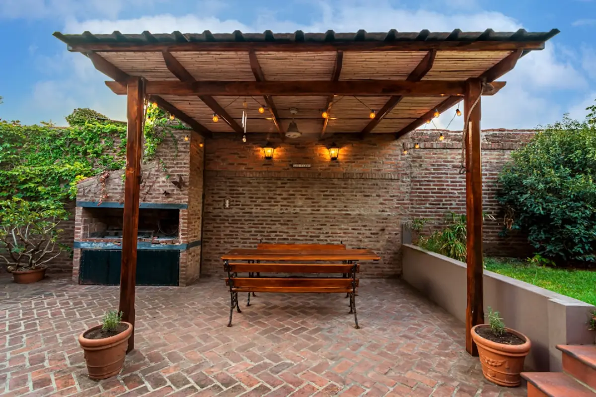 Timber pergola with a bench by a brick wall
