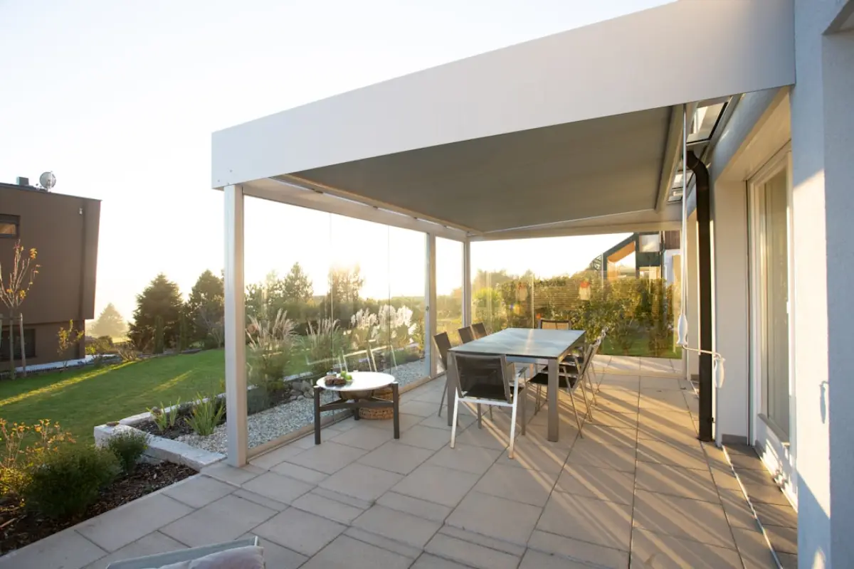 White aluminium pergola with a fixed roof over a terrace